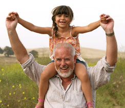 Smiling child riding on grandfather's shoulders